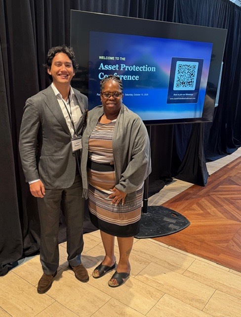 Two attendees in front of the conference welcome screen